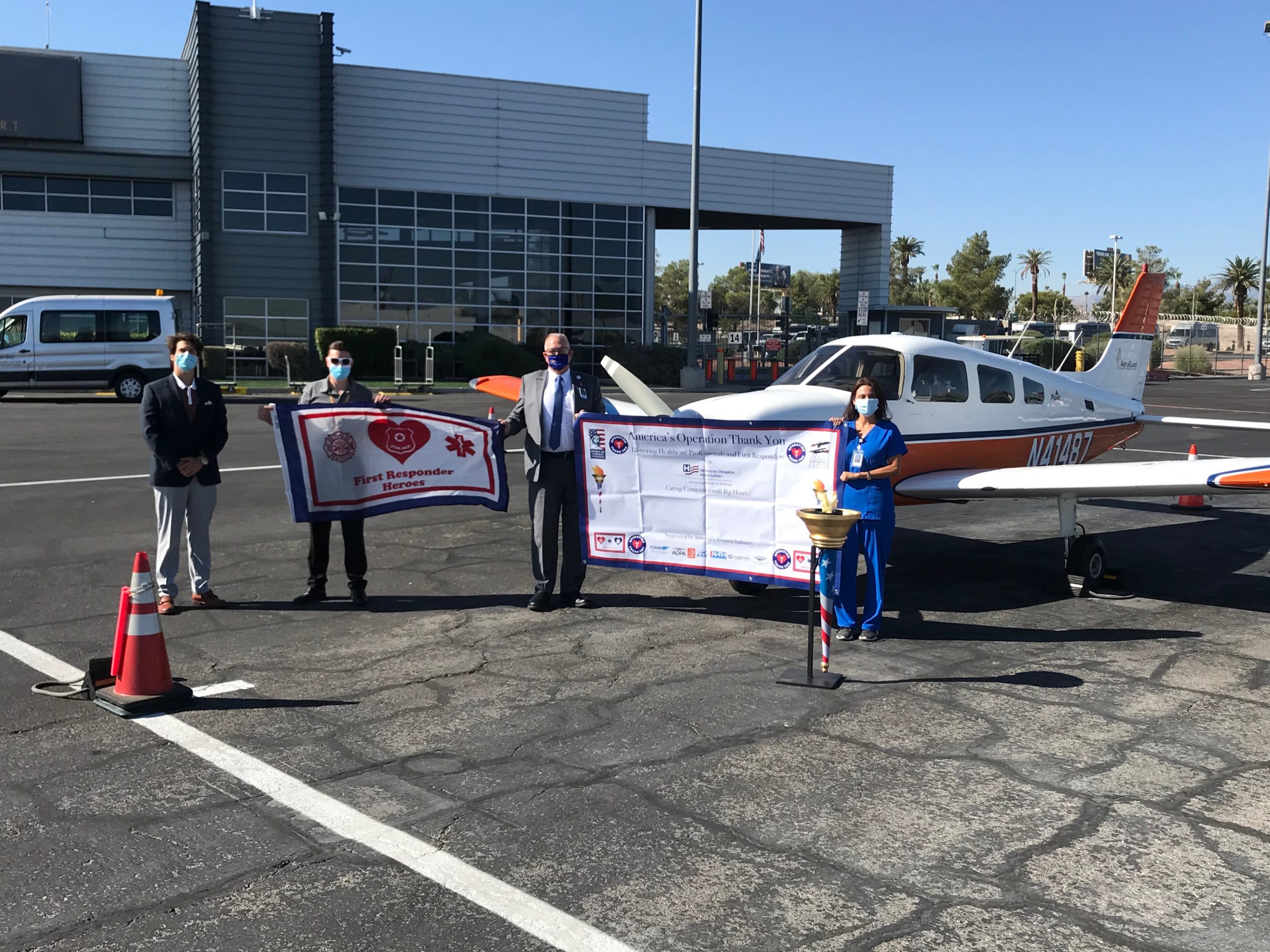 people gather and hold up operation thank you flag in front of aeroguard plane